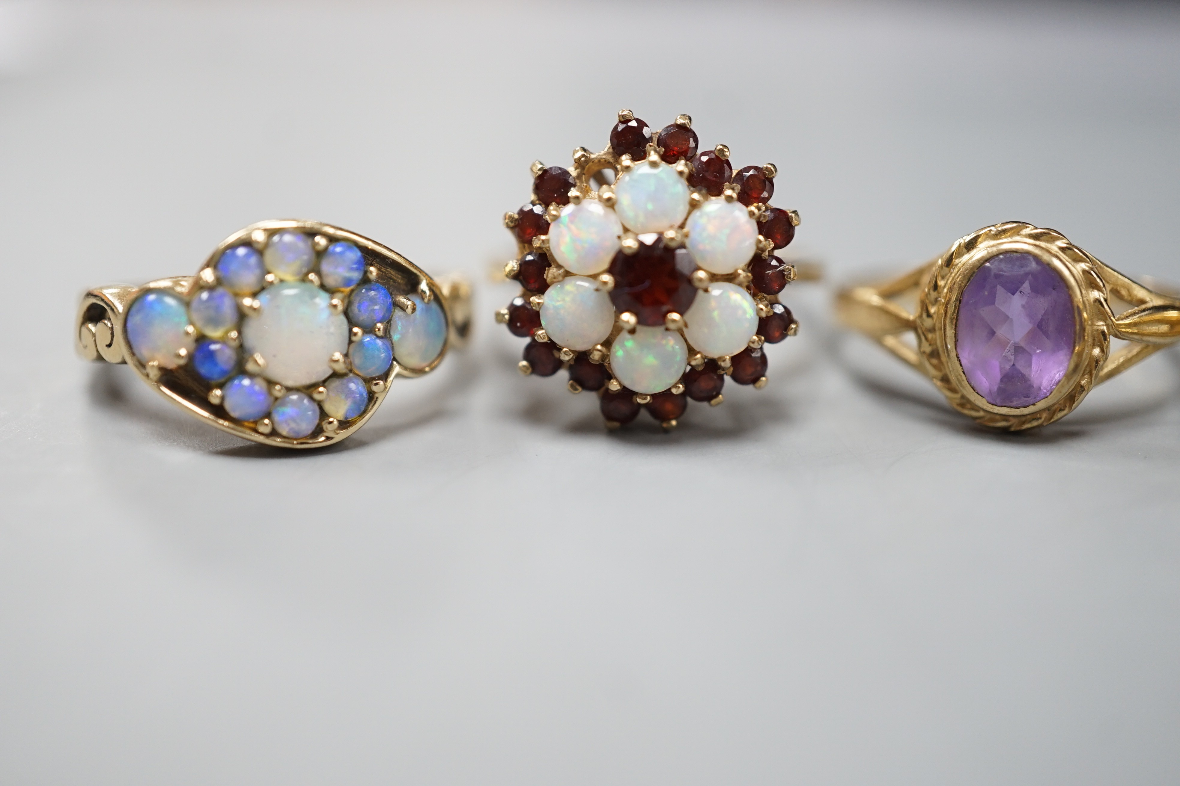 Five assorted modern 9ct gold and gem set dress rings, including, white opal cluster, garnet and white opal cluster and amethyst